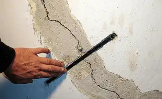A wall with a large crack is being inspected by a professional in Las Vegas, NV